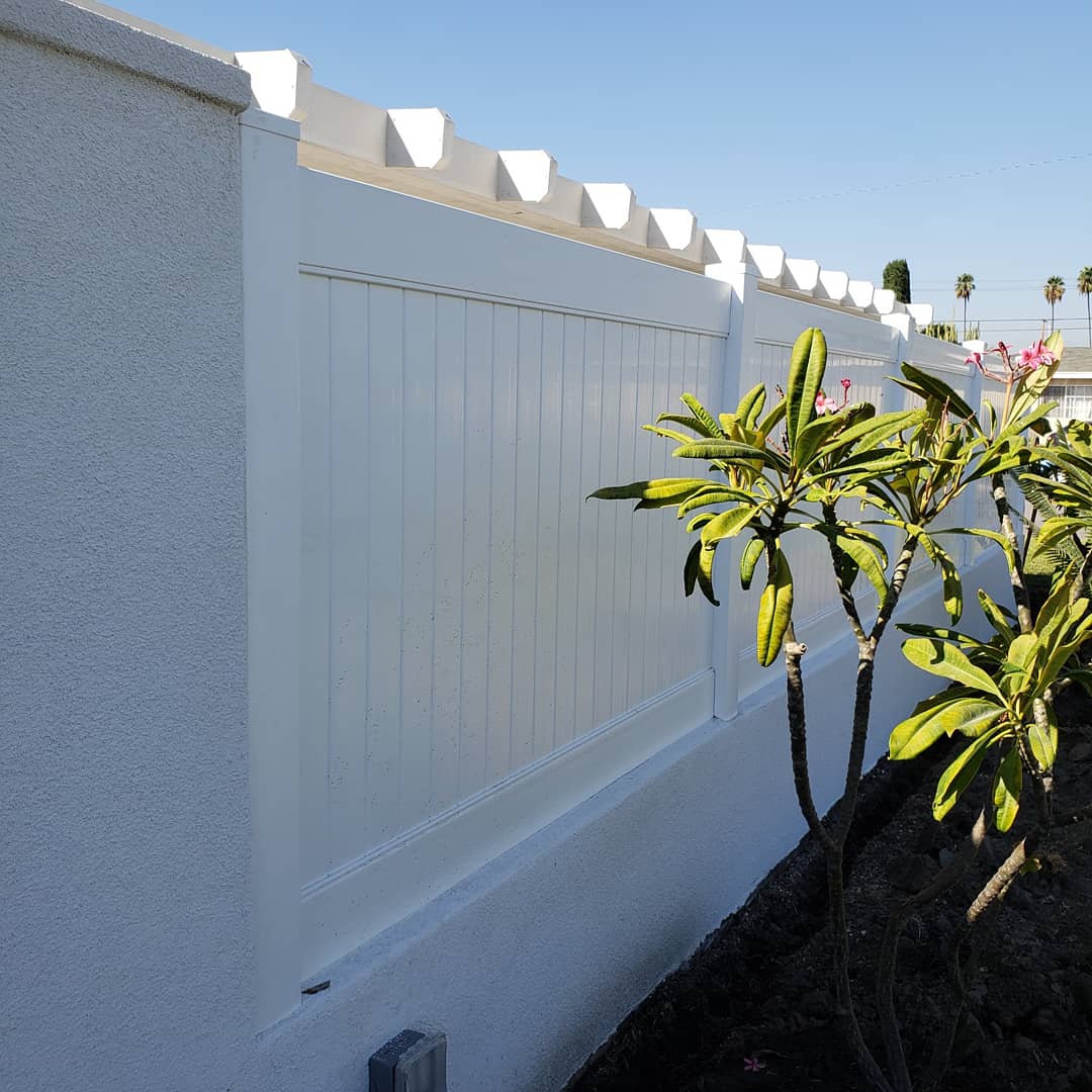A white vinyl fence in Irvine, CA, with a vibrant green plant